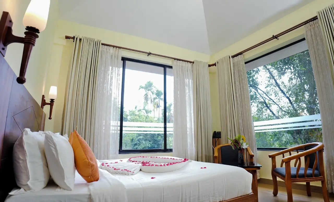 “Luxury bedroom with serene outdoor view in a Wayanad resort.”