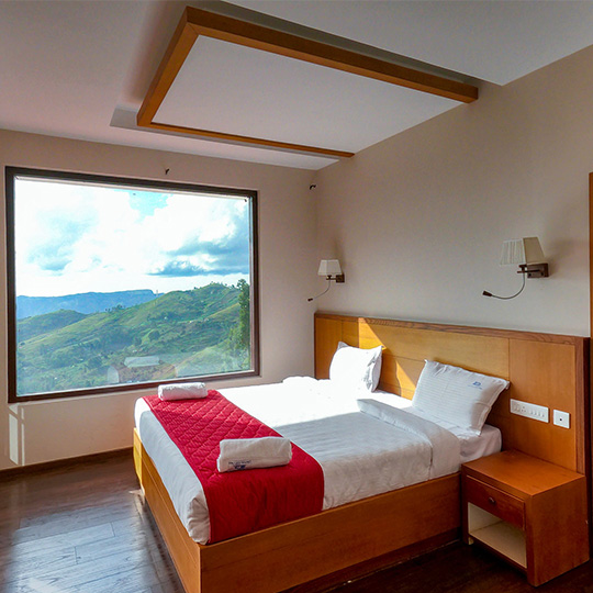 “Spacious family bedroom at Warmth Hill Crest in Kodaikanal featuring a cozy king-size bed, modern amenities, and a stunning valley view — perfect for family stays.”