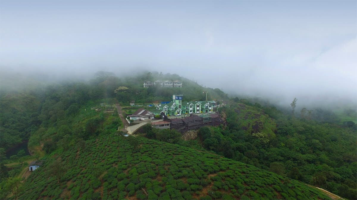 Panoramic hill view from Foggy Knolls Resort in Vagamon overlooking misty mountains, lush valleys, and tea plantations.
