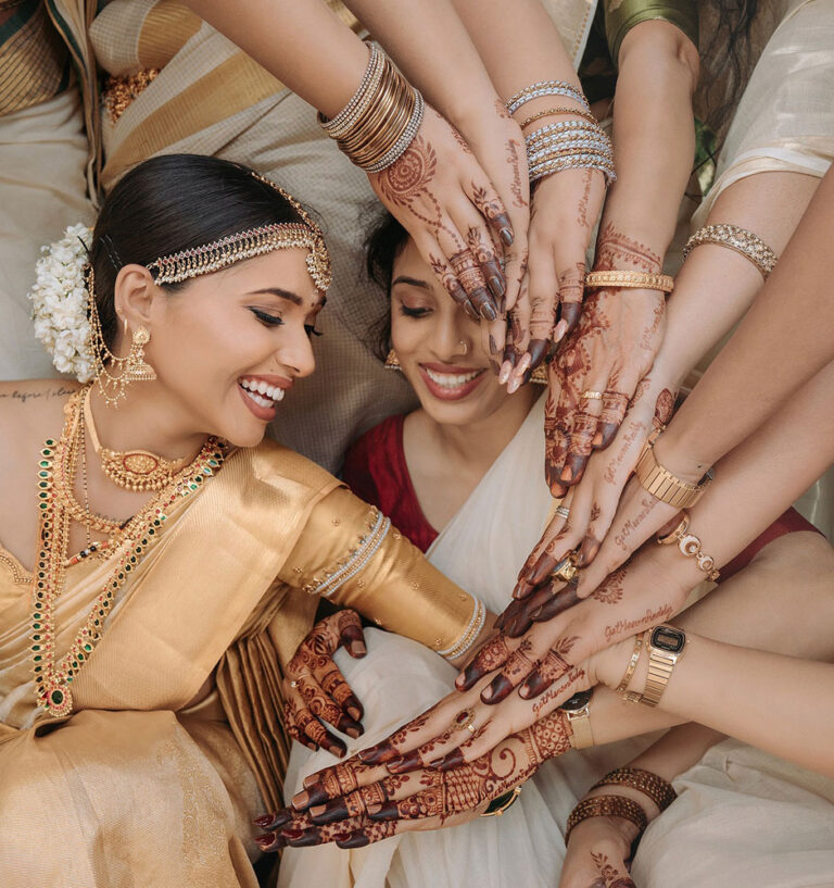 Bride with her friends showing their beautiful henna designs during a joyful wedding celebration.